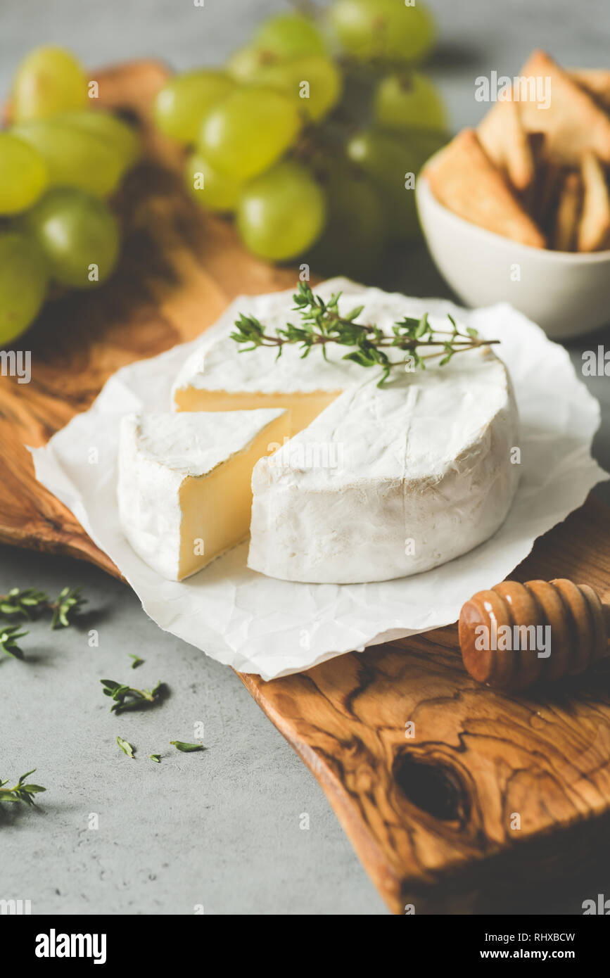 Brie ou camembert assiette de fromage avec des raisins, des craquelins et du miel Banque D'Images