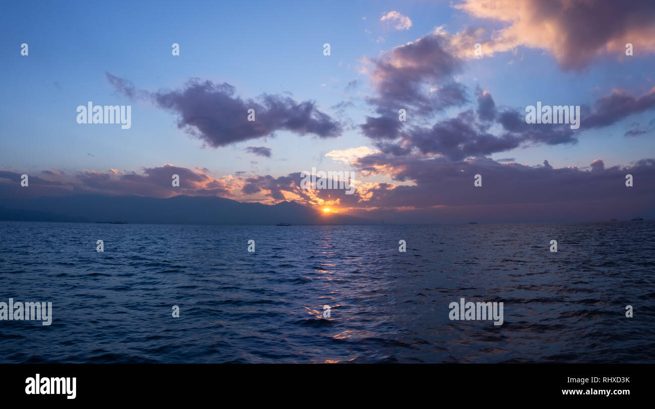 Vue sur le coucher de soleil sur la mer et entre les montagnes à partir de la ligne de ferry à Izmir, Turquie Banque D'Images