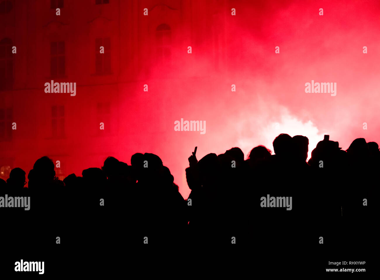 Silhouette d'une foule de fans de football (soccer) célébrant la victoire d'équipes et de pièces pyrotechniques et de tir des fusées éclairantes rouges dans la nuit. Banque D'Images