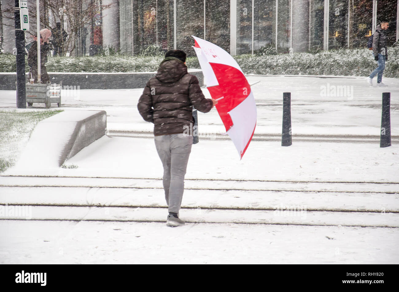 Rotterdam, Pays-Bas, le 22 janvier 2019 : personne aux prises avec un grand parapluie rouge et blanc lors d'une tempête de neige sur Kruisplein Banque D'Images