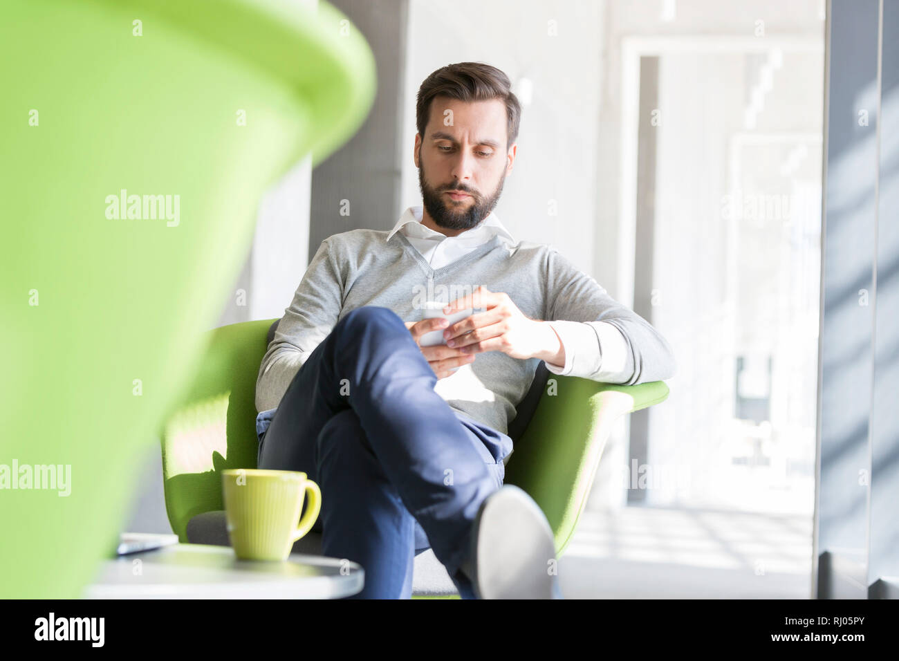 Confident businessman using smart phone in pause café au bureau Banque D'Images Confident businessman using smart phone in pause café au bureau Banque D'Images
