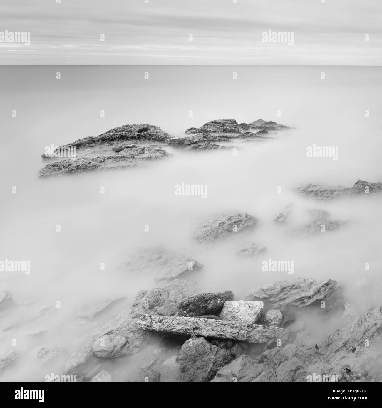 Une longue exposition mer paysage artistique. La lumière, l'eau et des pierres. Le noir et blanc Banque D'Images