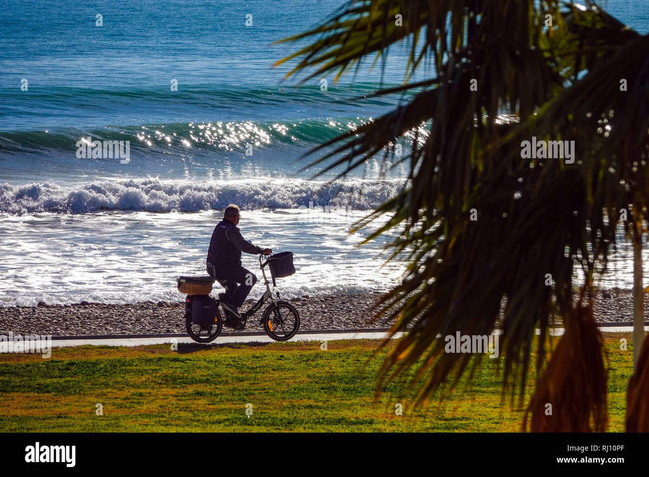 Personne plus âgée à vélo avec vélo électrique, la Promenade et la mer avec des vagues à Oropesa del Mar, Costa del Azahar, Province Castellon, Espagne, Oropesa Banque D'Images