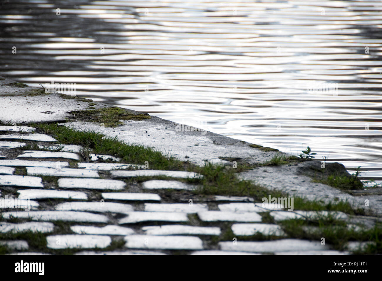 Pavés mouillés et ondulations dans l'eau de la Sheffield et Tinsley, Canal d'hiver humide jour abstract Banque D'Images