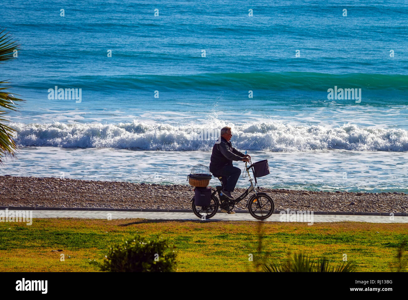 Personne plus âgée à vélo avec vélo électrique, la Promenade et la mer avec des vagues à Oropesa del Mar, Costa del Azahar, Province Castellon, Espagne, Oropesa Banque D'Images