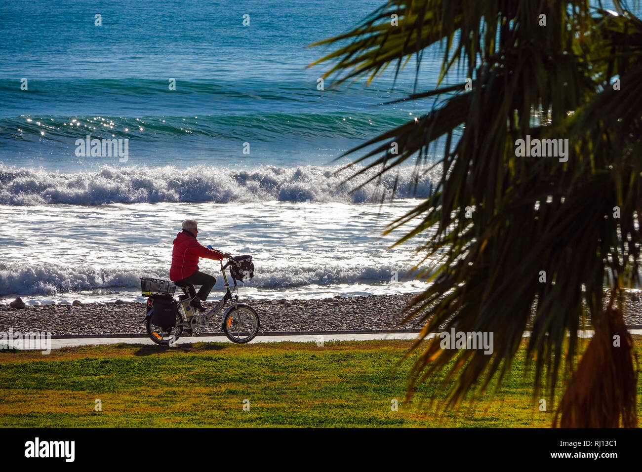 Personne plus âgée à vélo avec vélo électrique, la Promenade et la mer avec des vagues à Oropesa del Mar, Costa del Azahar, Province Castellon, Espagne, Oropesa Banque D'Images