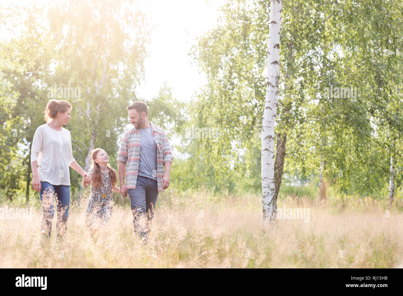 Smiling girl walking avec les parents contre des arbres sur terrain Banque D'Images