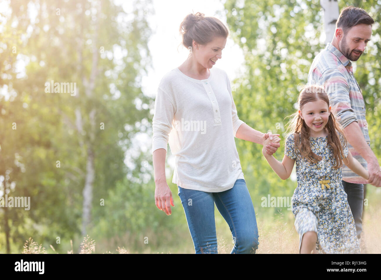 Smiling girl walking avec les parents contre des arbres sur terrain Banque D'Images