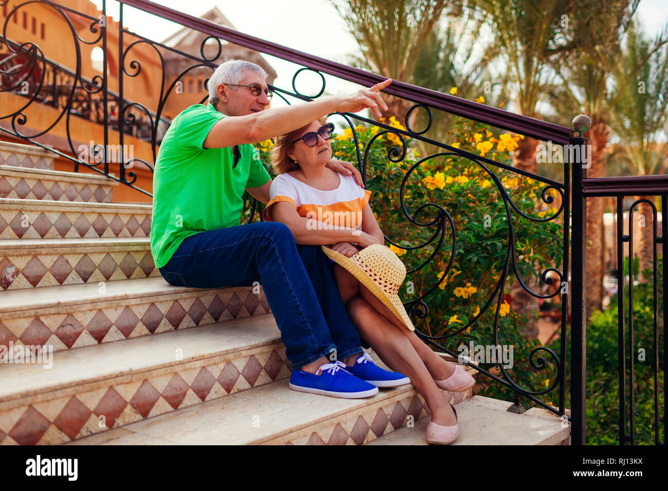 Senior couple sitting on stairs sur territoire de l'hôtel et de pointage à vue. Les personnes bénéficiant de vacances. Concept de voyage Banque D'Images