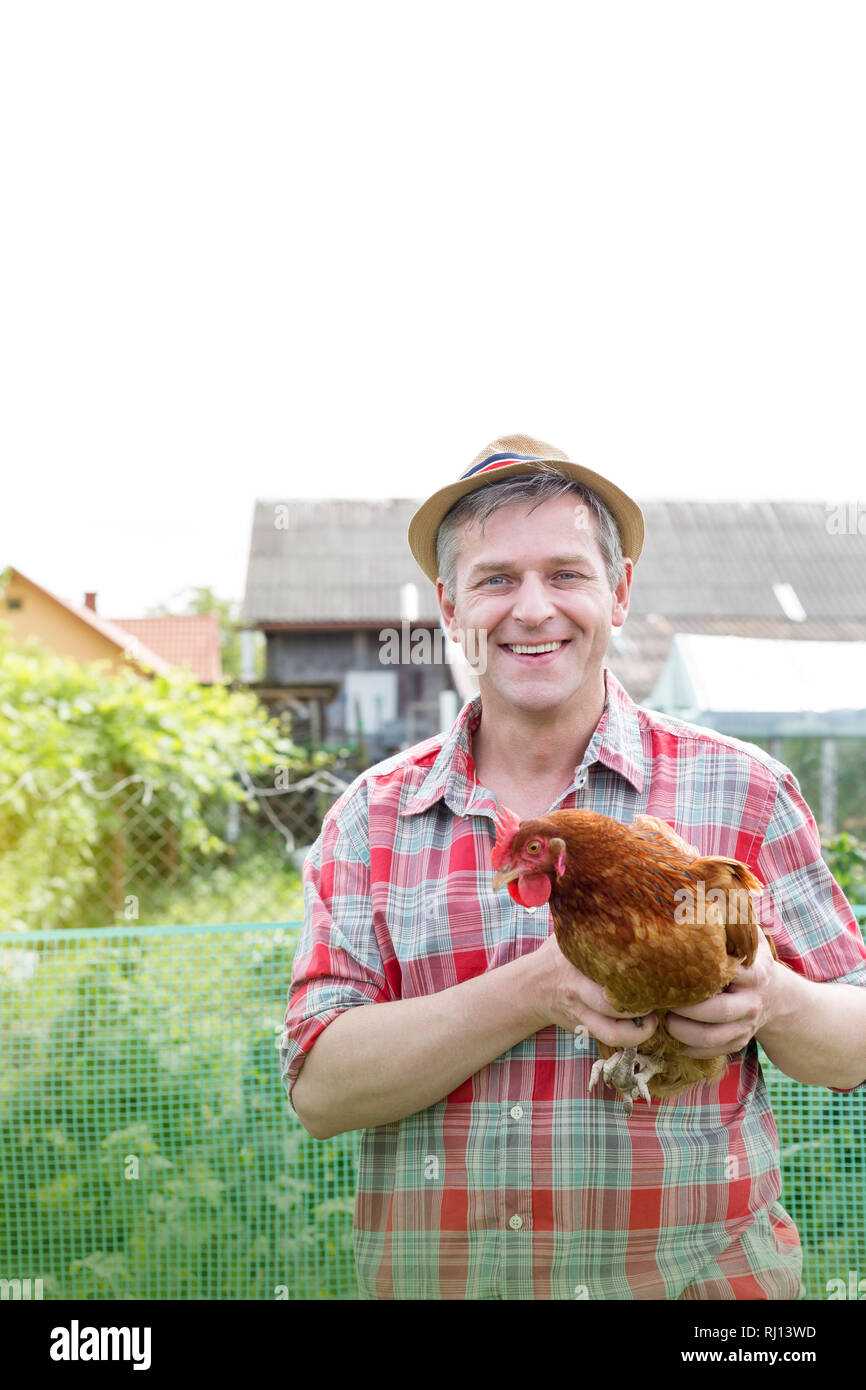 Portrait of smiling farmer holding hen farm Banque D'Images