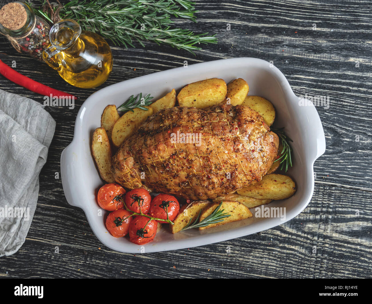 Rôti de porc grillée, rouleau avec pommes de terre et de tomate dans la rôtissoire Banque D'Images