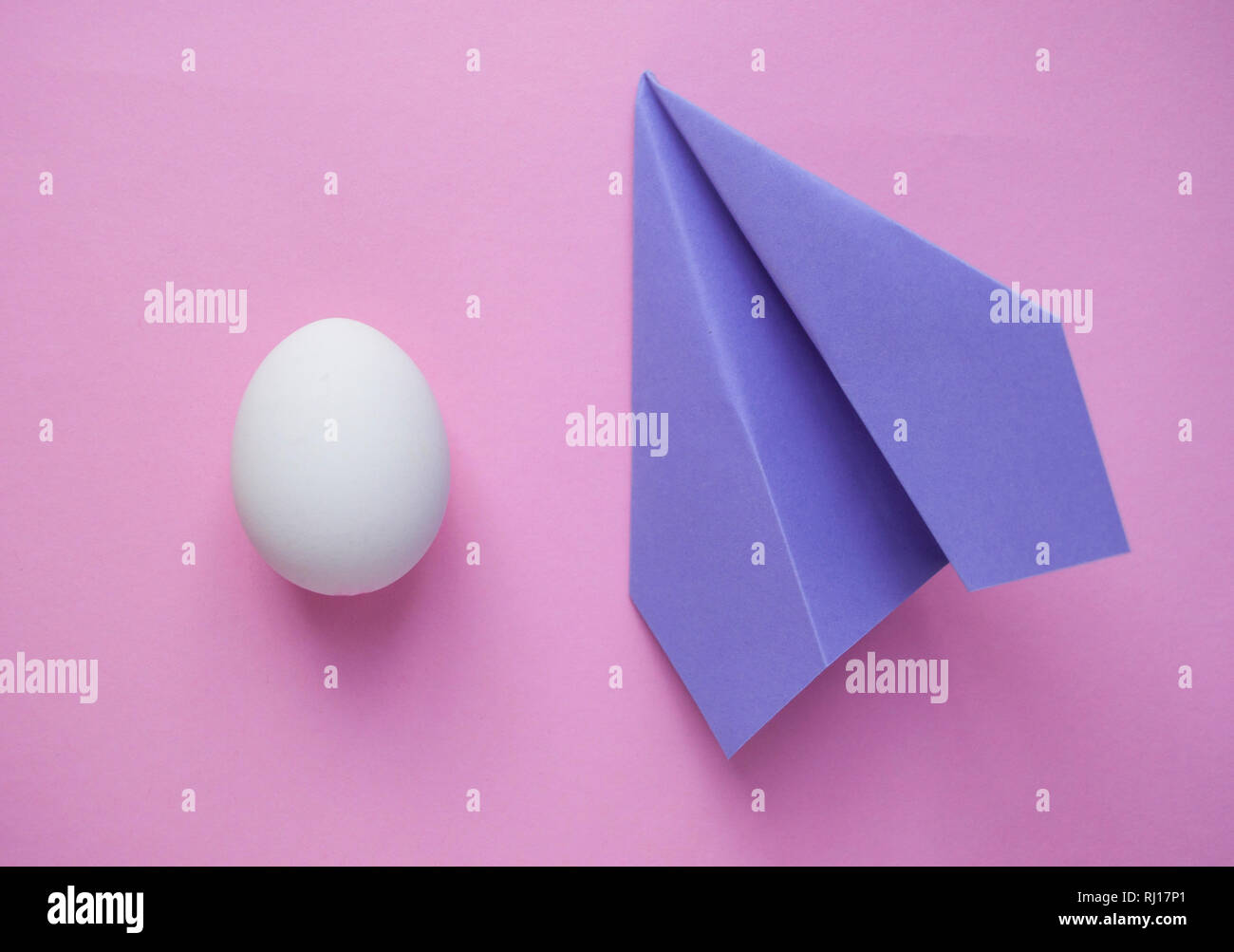 Un seul œuf blanc sur fond rose avec paper plane et copyspace. Concept minimaliste. Banque D'Images