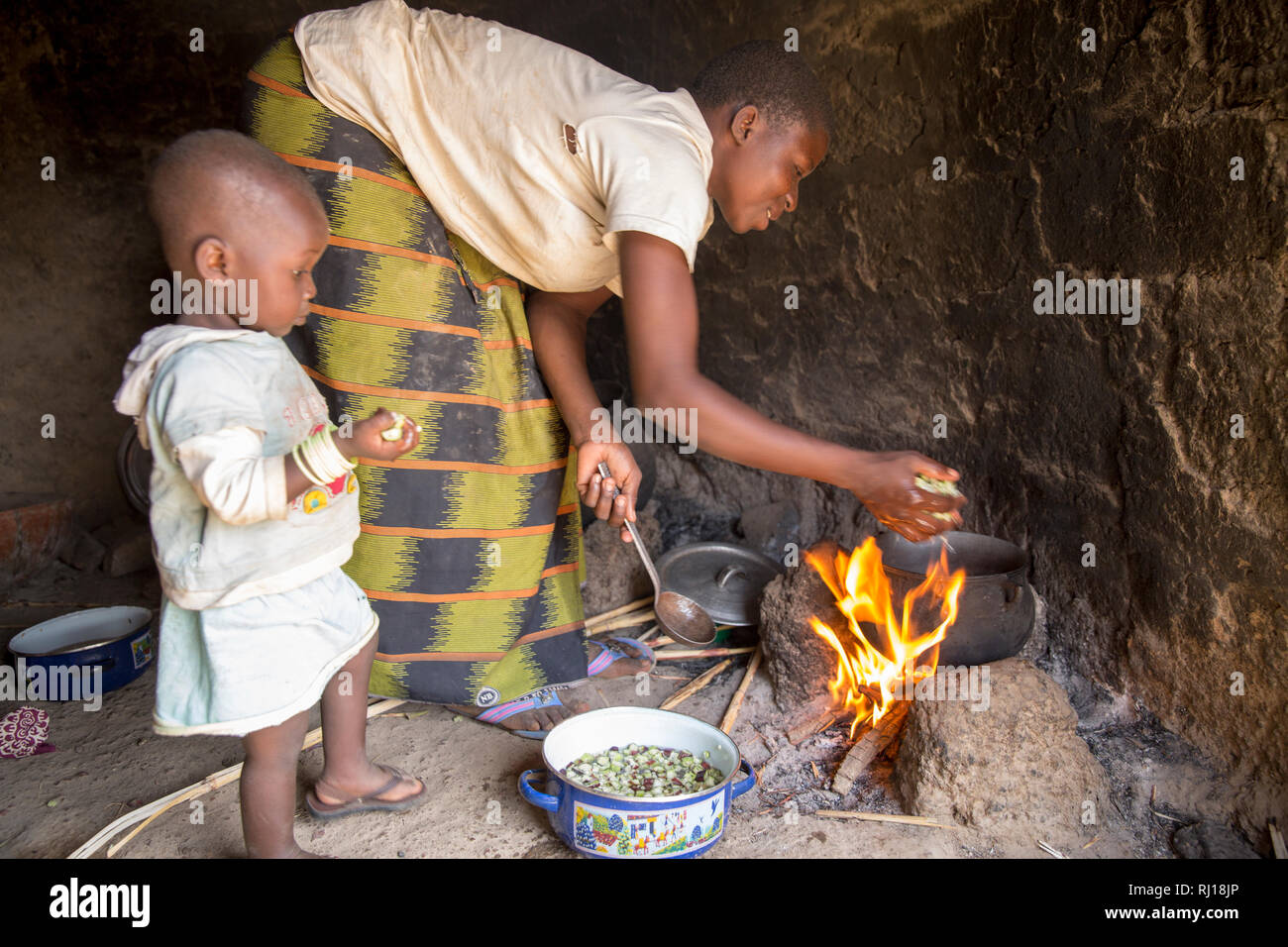 Village de samba, Province de Yako, Burkina Faso : Collette Guiguemde, 26 avec son bébé divin Ornela Zoundi, 18 mois, prépare un repas pour ses enfants et ses beaux-parents avec l'okra qu'elle vient de récolter. Banque D'Images