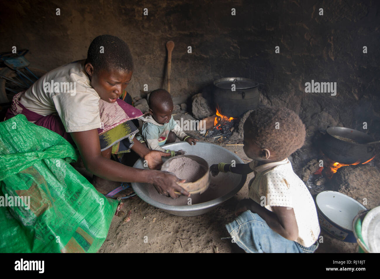 Village de samba, Province de Yako, Burkina Faso : Collette Guiguemde, 26 avec son bébé et ses quatre -ans, prépare un repas avec l'okra qu'elle vient de récolter, faire une bouillie de sorgho pour aller avec. Banque D'Images