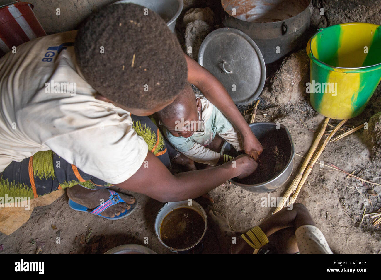 Village de samba, Province de Yako, Burkina Faso : Collette Guiguemde, 26 se lave les mains de bébé Ornela avant qu'ils partagent le repas qu'elle vient tout juste cuits. Banque D'Images