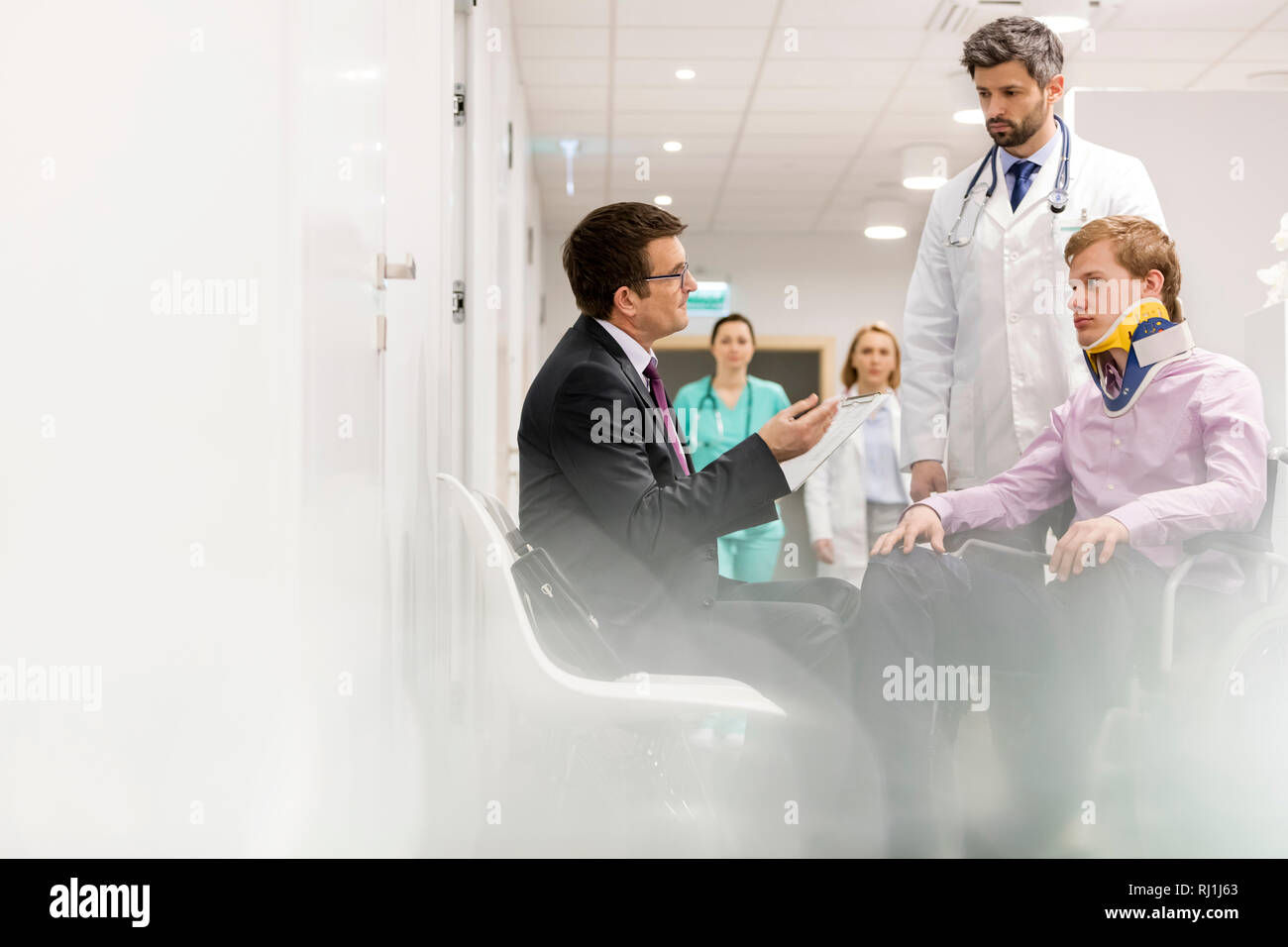 Parler à un Spécialiste mobilité l'homme tandis que les médecins à in hospital corridor Banque D'Images