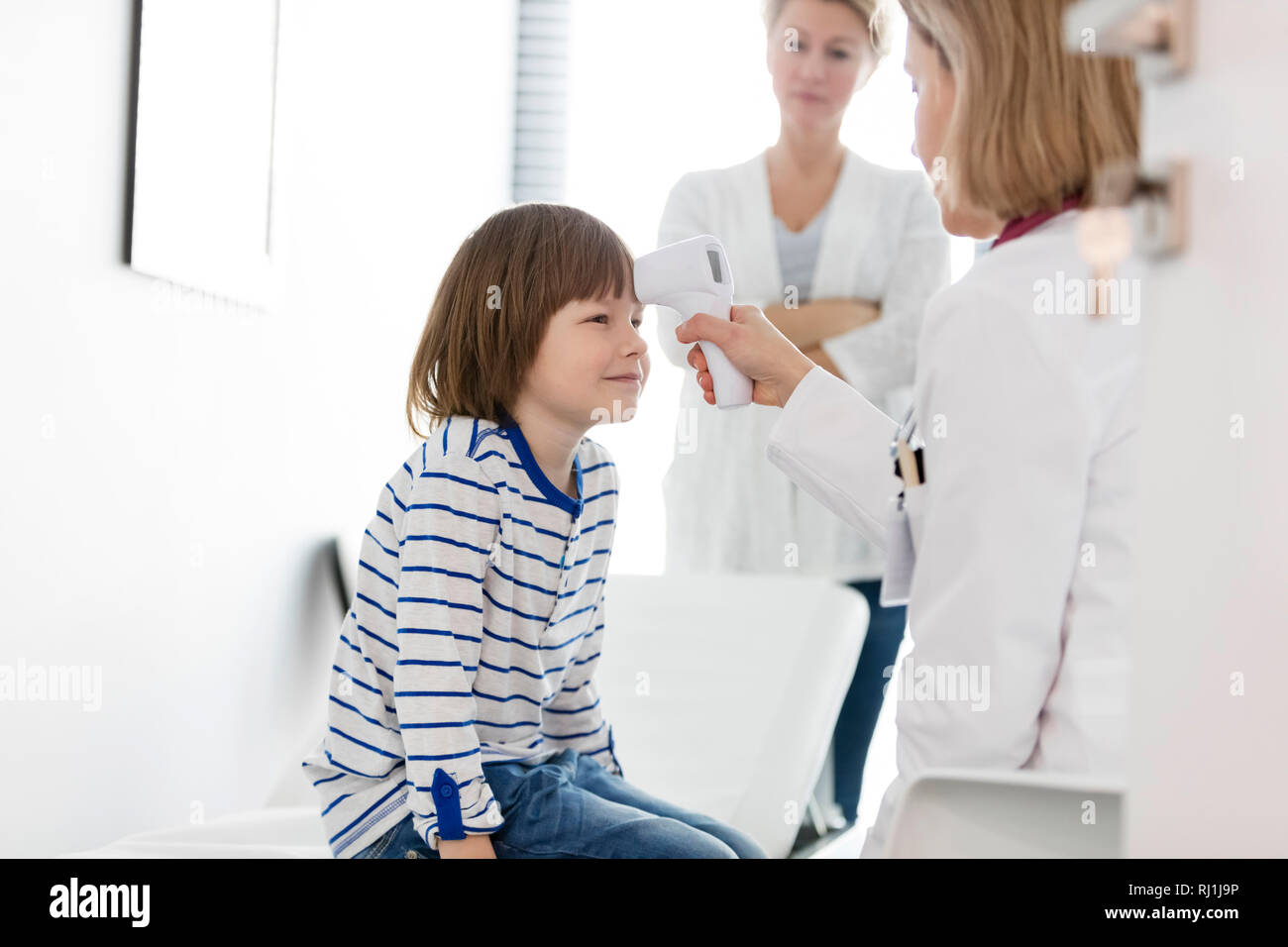 Mesure de la température du jeune médecin avec un thermomètre à infrarouge à l'hôpital Banque D'Images