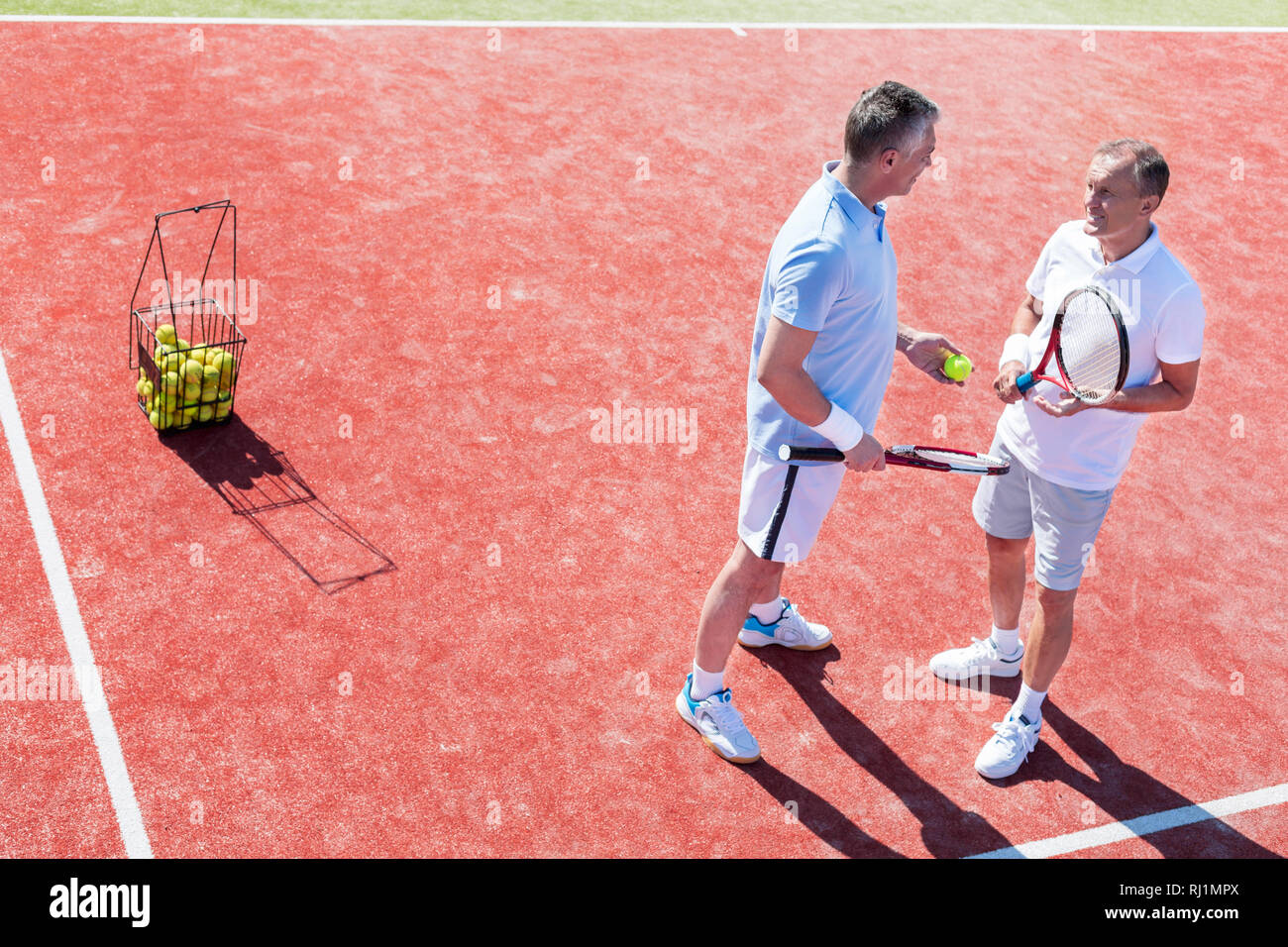 Toute la longueur d'hommes parler en se tenant sur le tennis au cours de match Banque D'Images