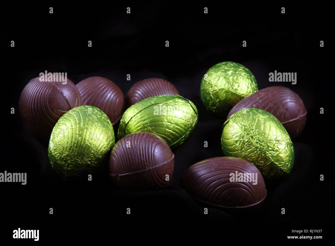 Pile de citron vert ou jaune enveloppé d'aluminium et les oeufs de pâques en chocolat emballé sur un fond noir. Banque D'Images