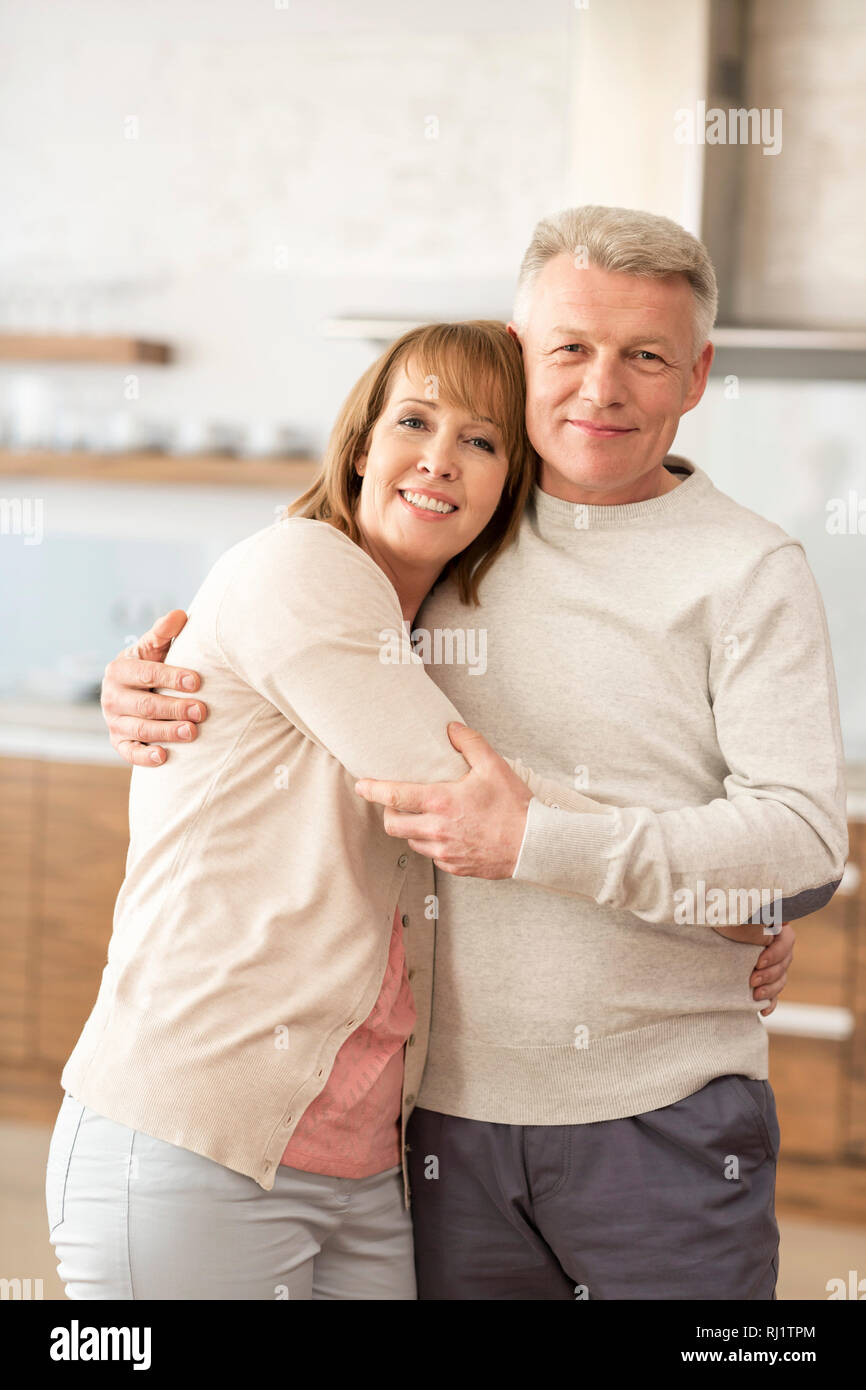 Portrait of mature couple embracing while standing at home Banque D'Images
