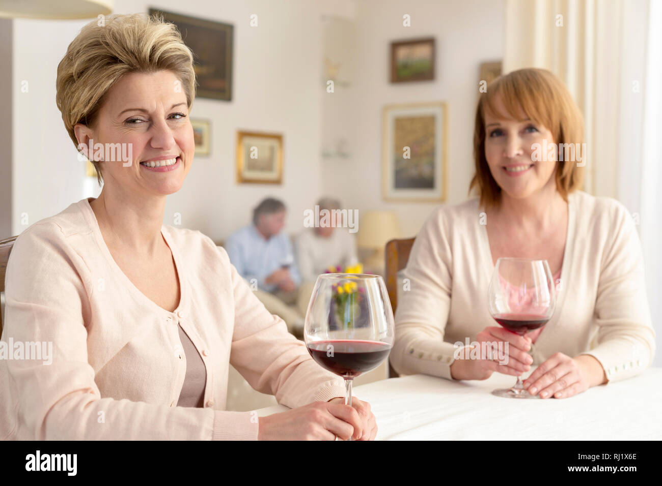 Portrait of smiling mature women sitting with wineglasses at table à manger Banque D'Images