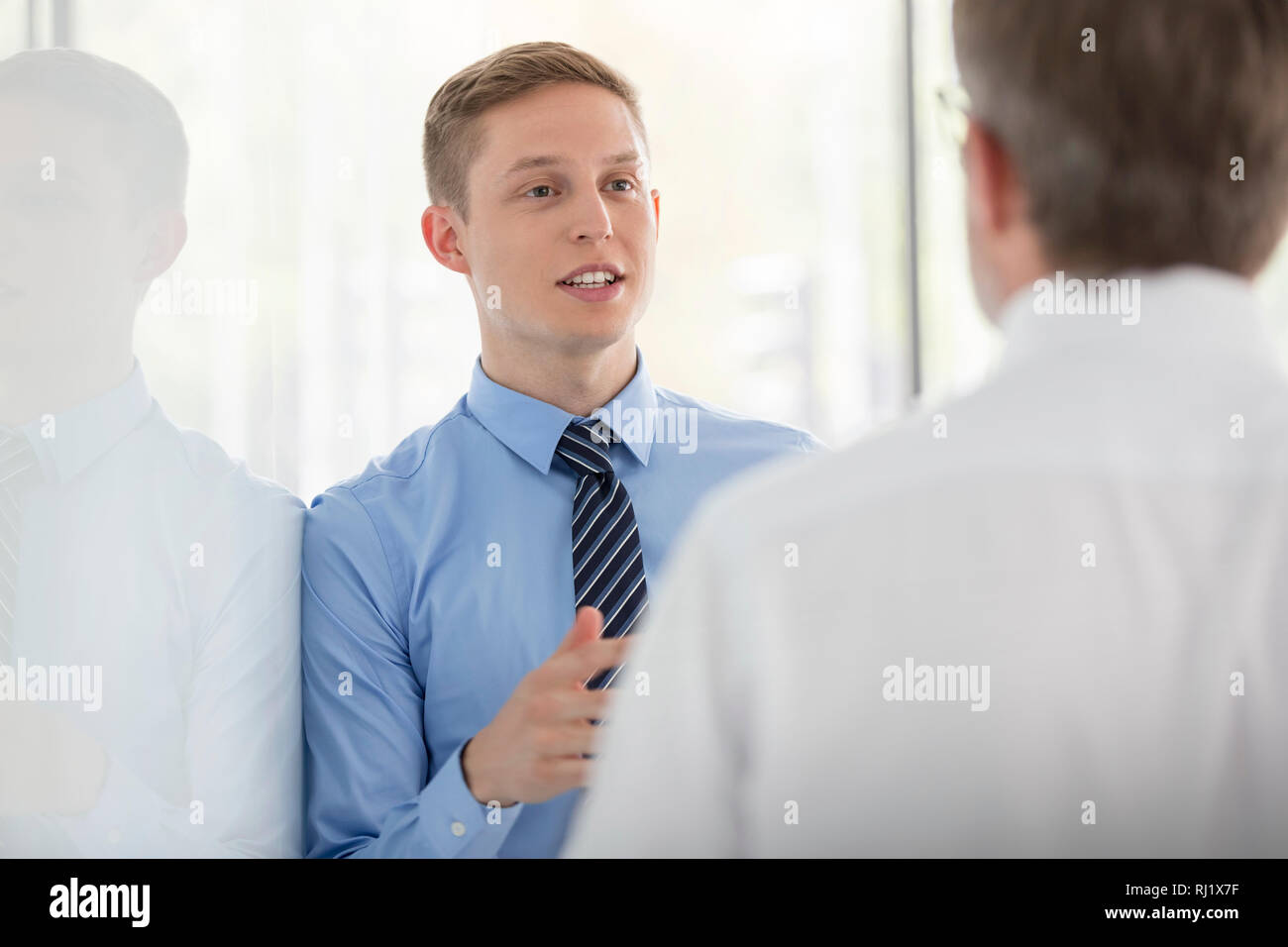 Des collègues de discuter par wall at office Banque D'Images