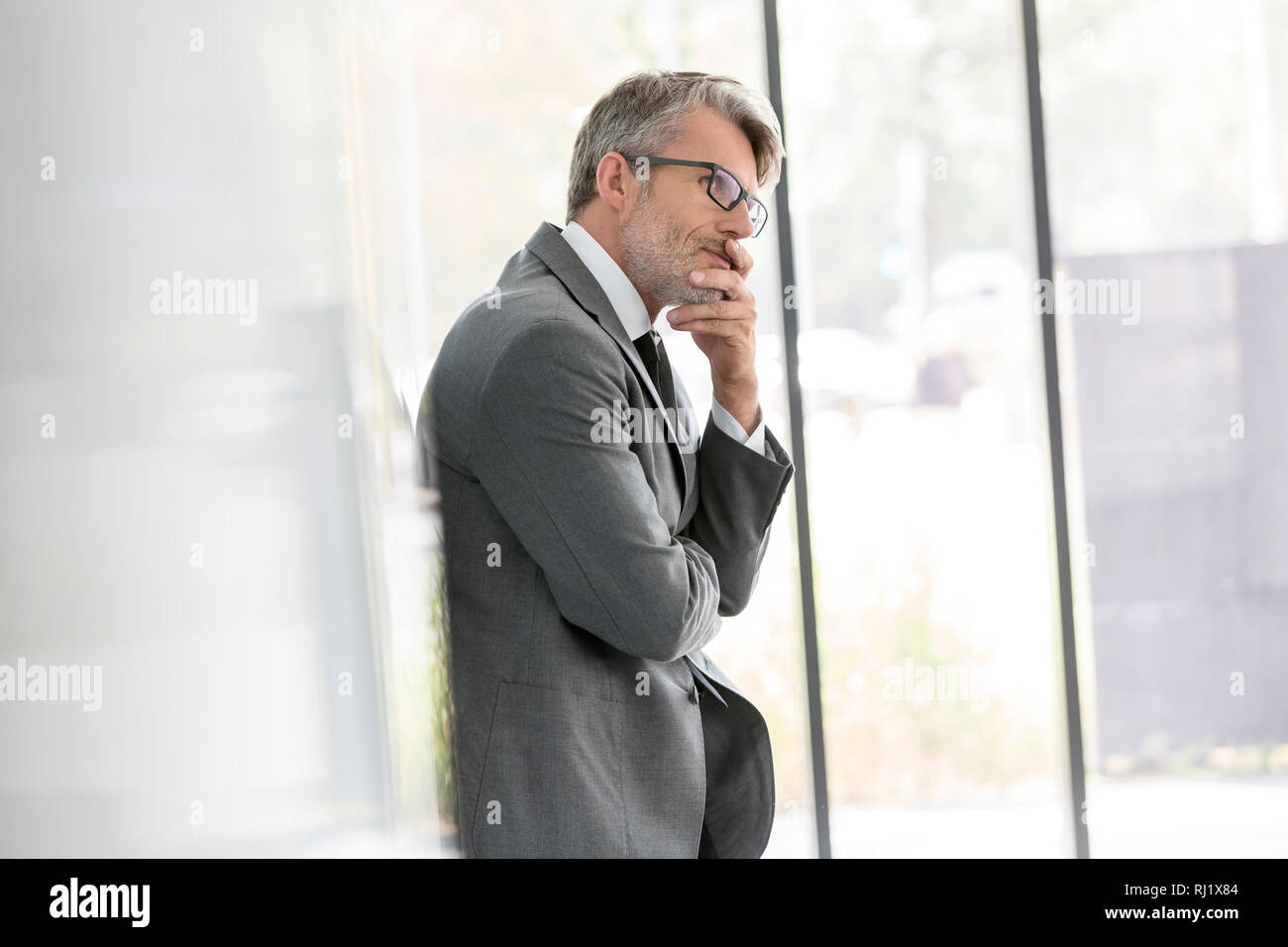 Thoughtful mature businessman looking away while standing at office Banque D'Images