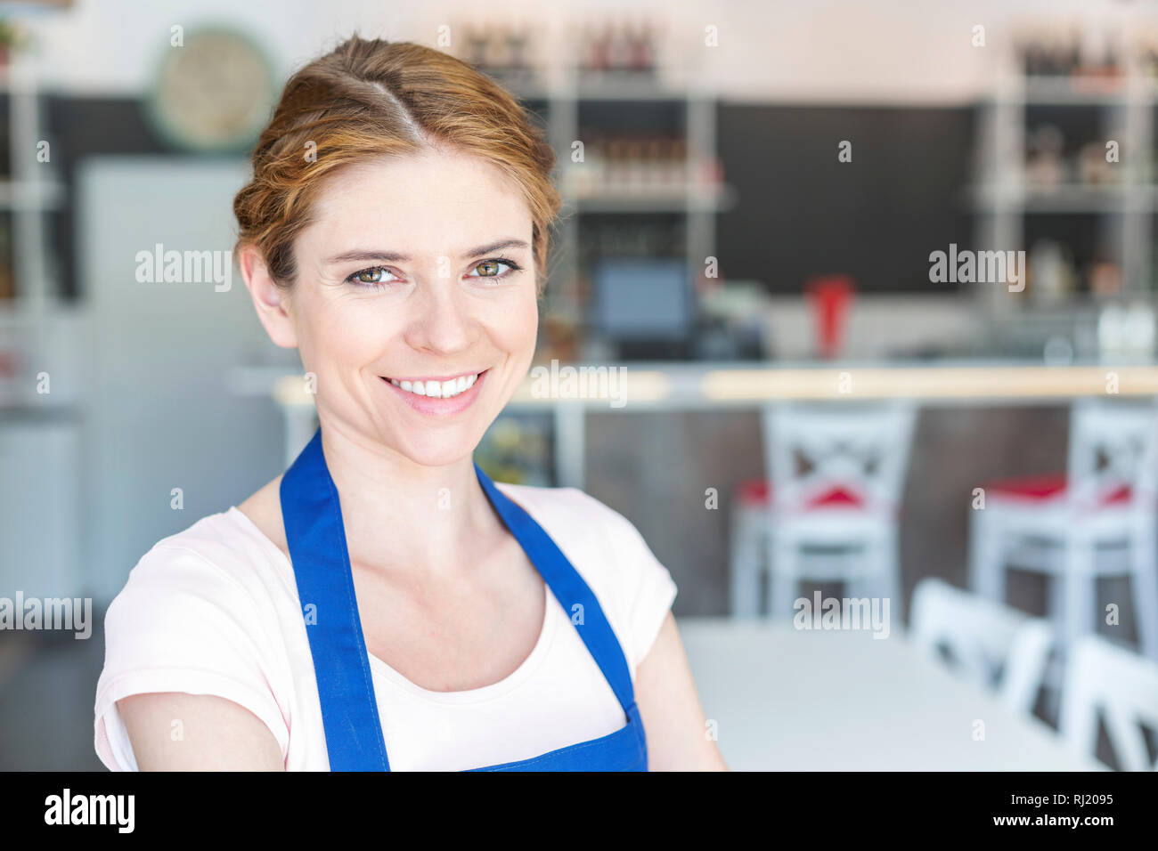Closeup portrait of smiling young waitress standing at restaurant Banque D'Images Closeup portrait of smiling young waitress standing at restaurant Banque D'Images
