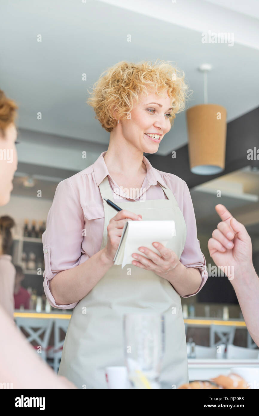 Smiling waitress de man sitting at restaurant Banque D'Images