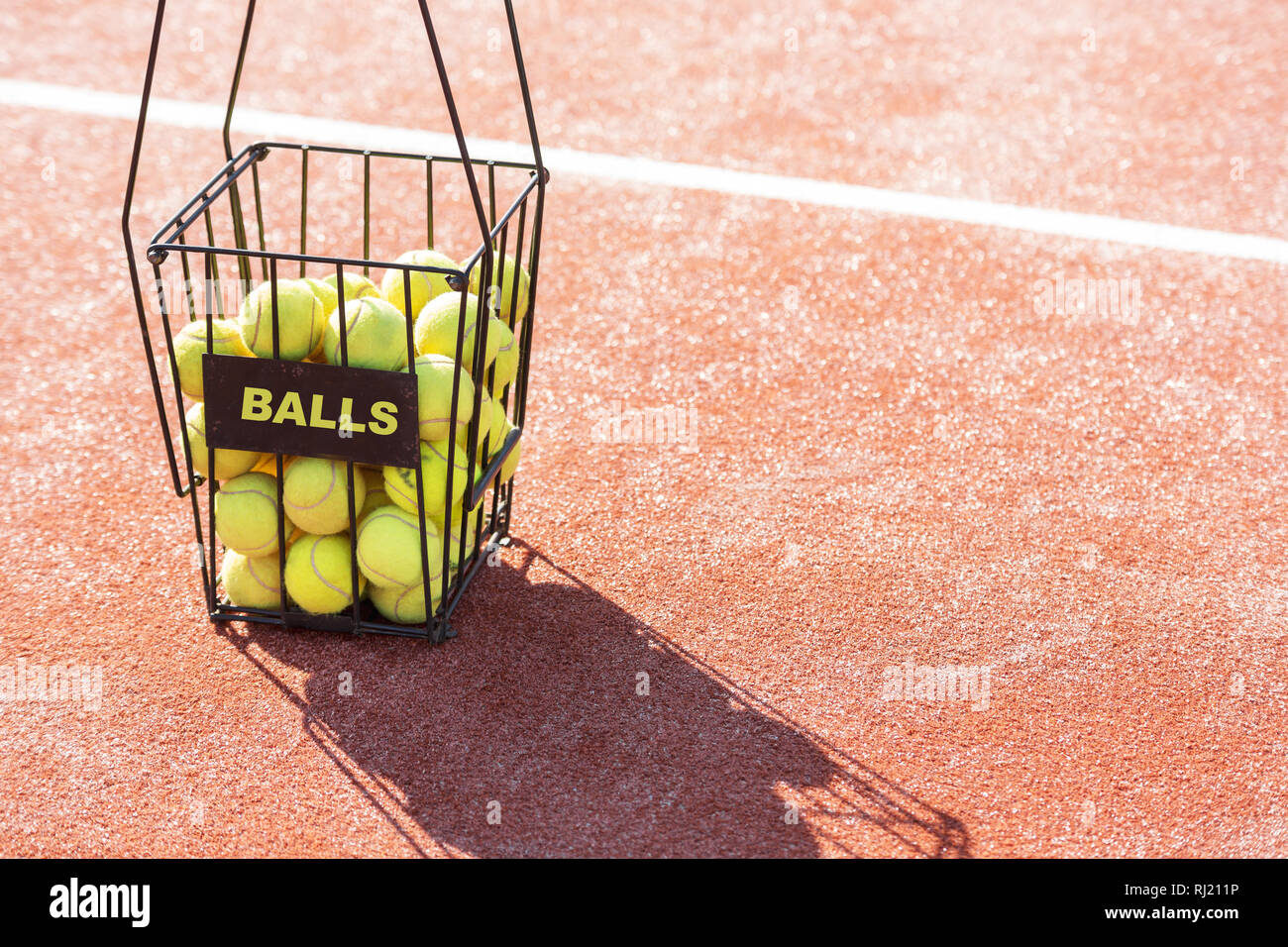 Portrait de boules dans le panier métallique avec étiquette sur un court de tennis Banque D'Images