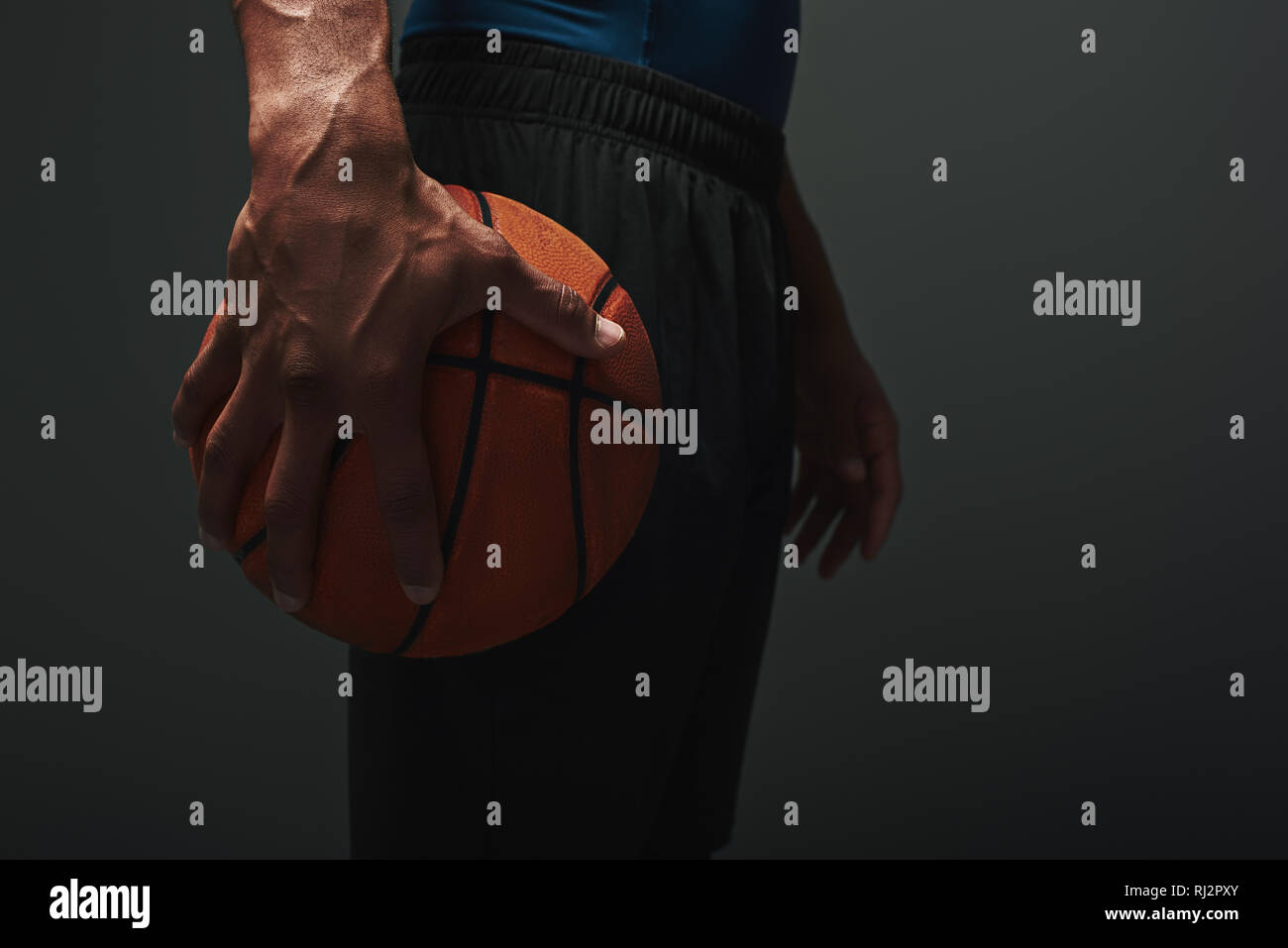 Close up of basket-ball en short noir isolés sur fond sombre et tenant une balle Banque D'Images