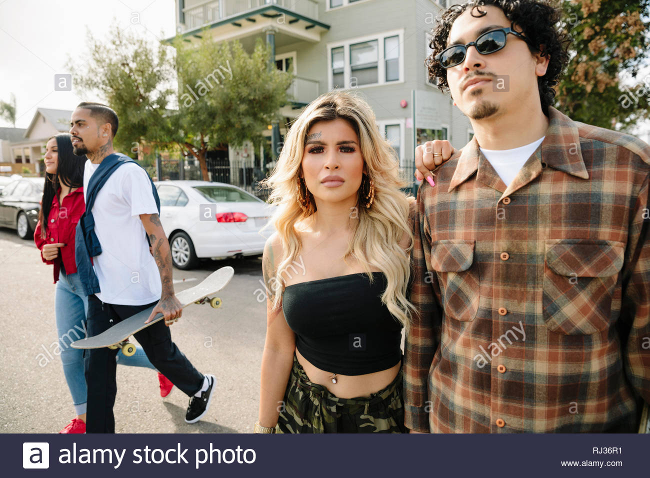 Couples avec Latinx crossing street skateboard Banque D'Images