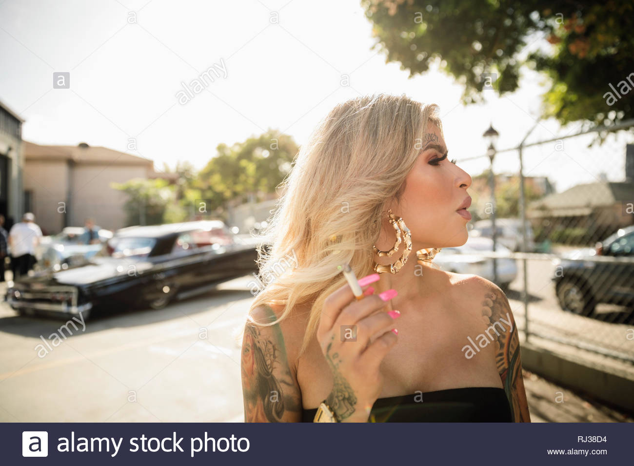 Jeune femme Latinx de tatouages cigarette dans parking Banque D'Images