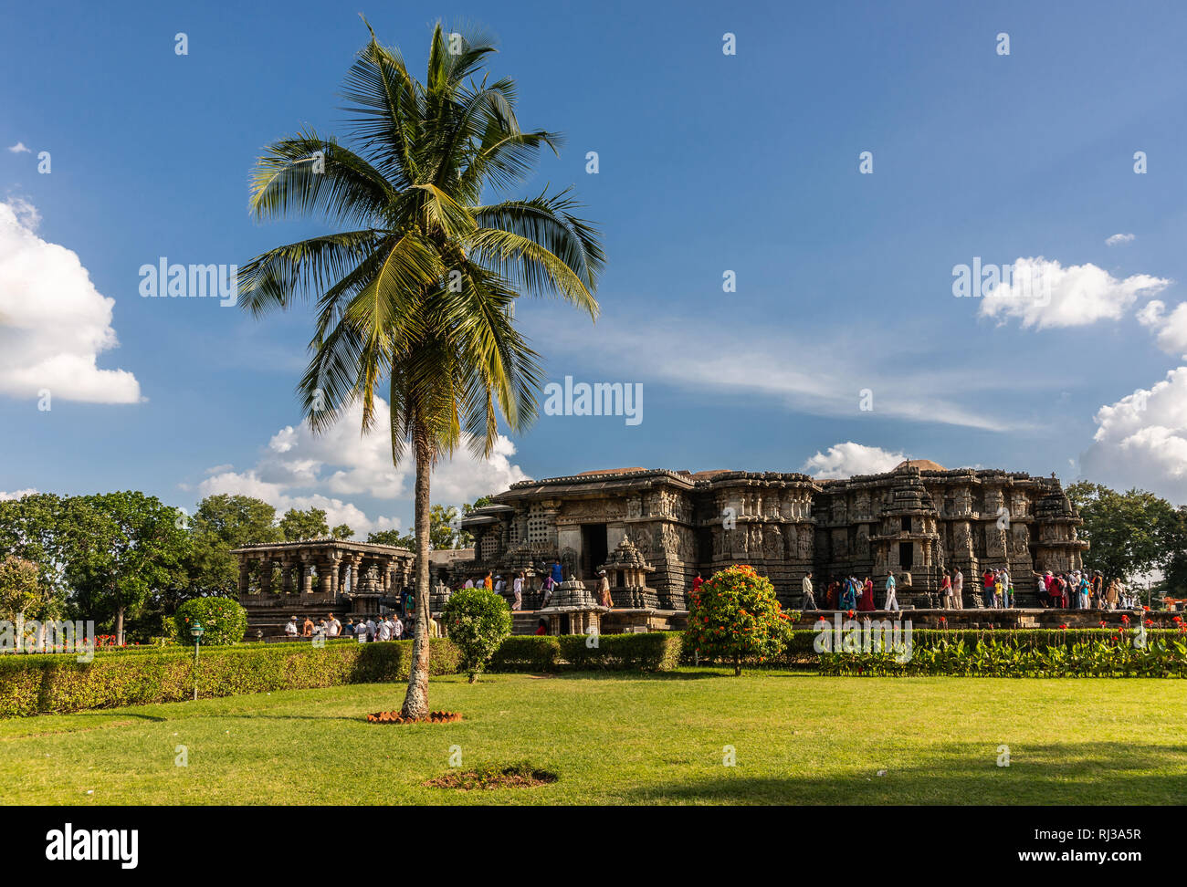 Halebidu, Karnataka, Inde - Novembre 2, 2013 : Marron Pierre télévision Hoysaleswara temple de Shiva dans son jardin verdoyant avec des palmiers et beaucoup de dévots Banque D'Images