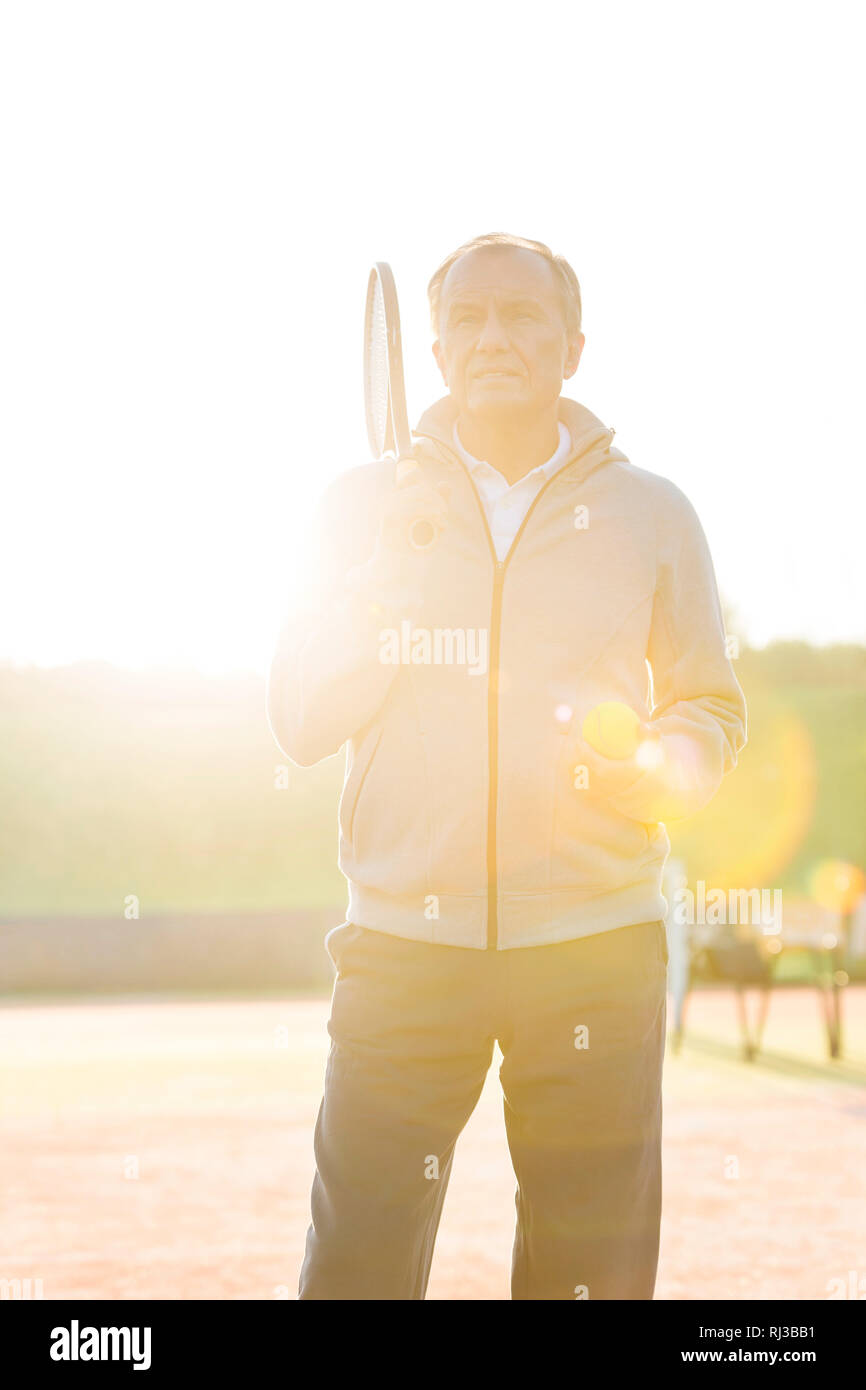 Retour allumé de man avec raquette de tennis et la balle contre le ciel clair aux beaux jours Banque D'Images