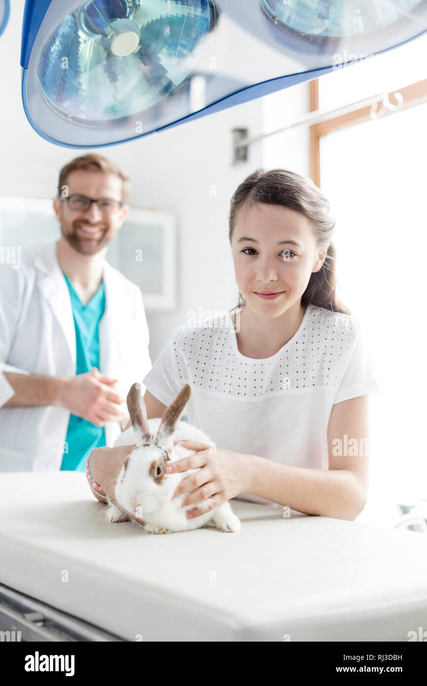 Portrait de fille avec lapin sur lit contre médecin clinique vétérinaire Banque D'Images