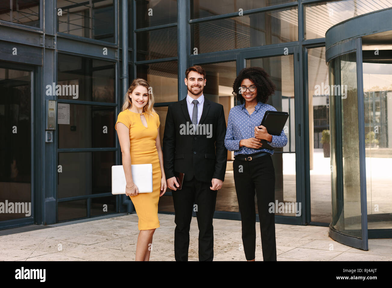 Jeunes collègues d'affaires prospères debout ensemble. homme d'affaires avec des collègues féminins dans l'immeuble de bureaux d'entreprise. Banque D'Images