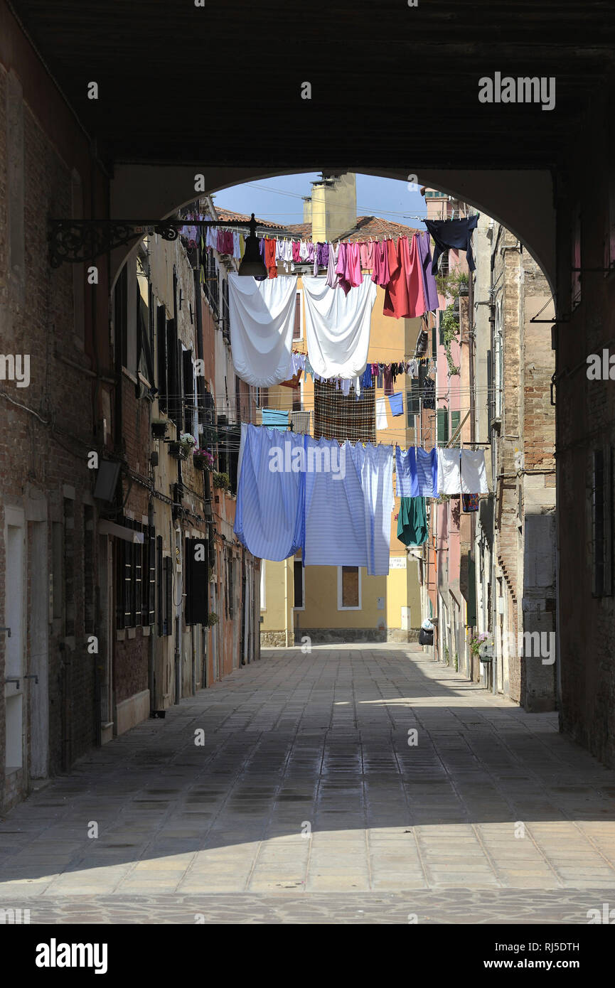 Wäsche hängt zum Trocknen auf Wäscheleinen, die zwischen Häusern gespannt ist Banque D'Images
