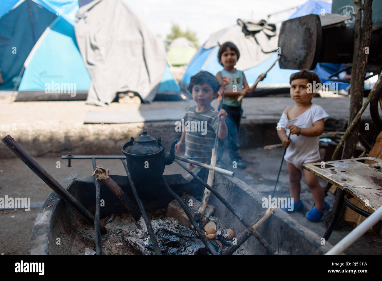 Eine Kochstelle wird von Jungs bewacht 3. Von Flüchtlingscamp Idomeni in Griechenland an der Grenze nach Nombre d'habitants, avril 2016. Banque D'Images