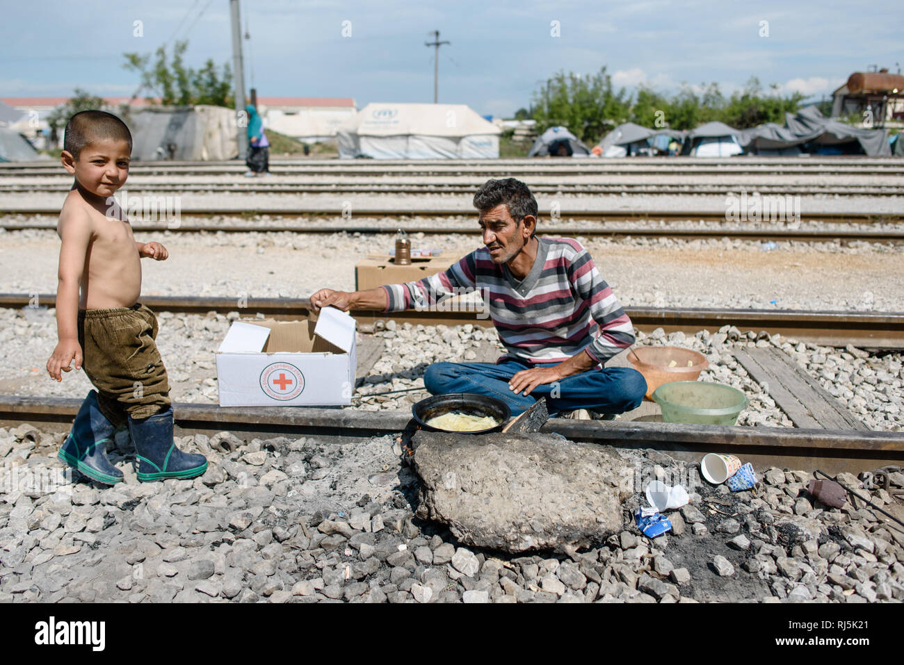 Ein Vater kocht für sich und seinen Sohn ein Mahlzeit auf den Zuggleisen. Von Flüchtlingscamp Idomeni in Griechenland an der Grenze nach Nombre d'habitants, un Banque D'Images