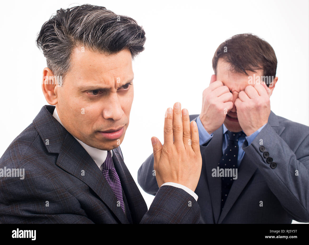 Deux hommes d'affaires ayant un argument, l'un ne veut pas écouter et l'autre pleure, sur un fond blanc. Banque D'Images