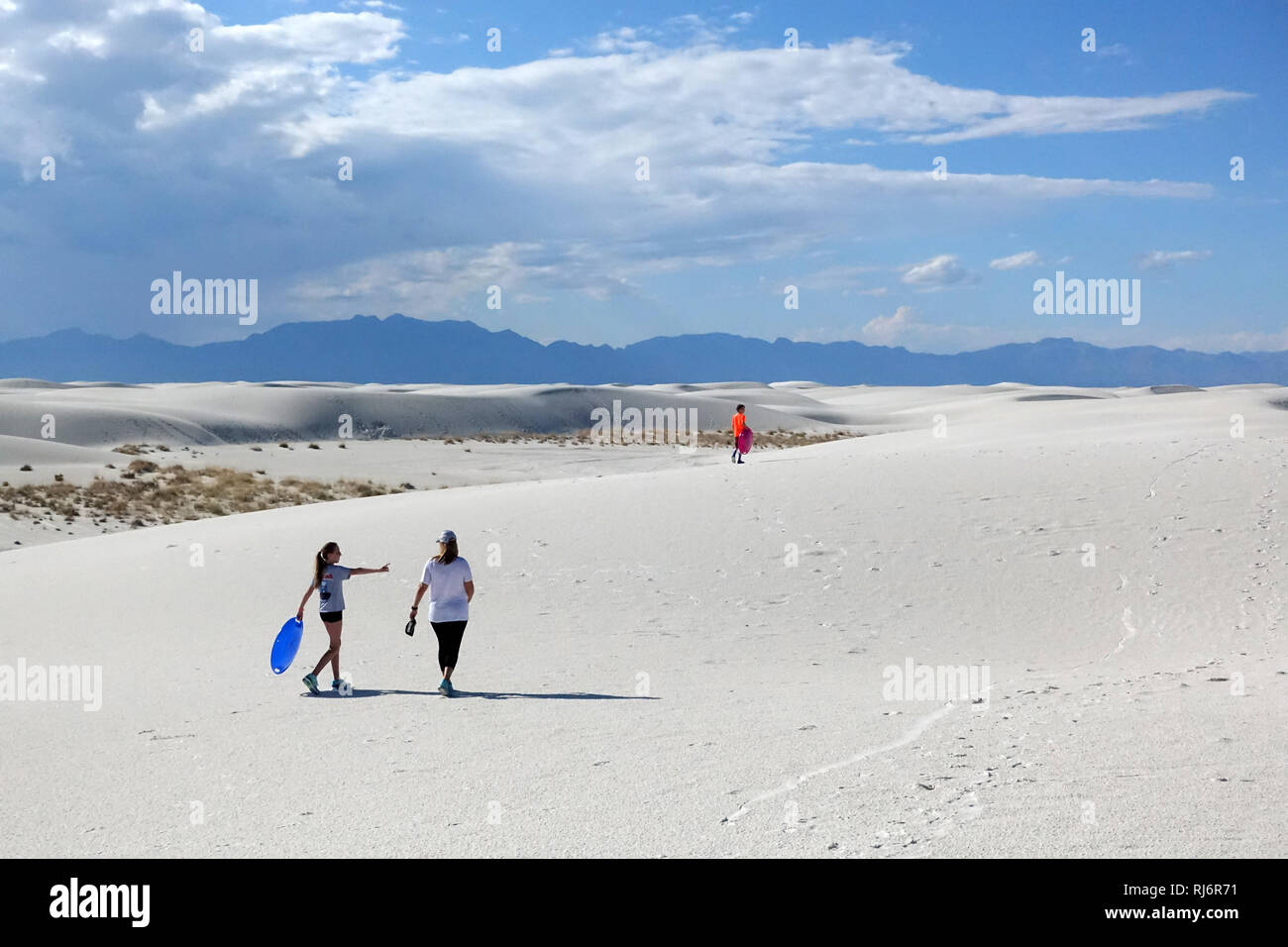 Les enfants chercher un endroit pour aller en luge sur le sable à White Sands, au Nouveau Mexique. Une attraction touristique doit cesser et Monument National. Banque D'Images