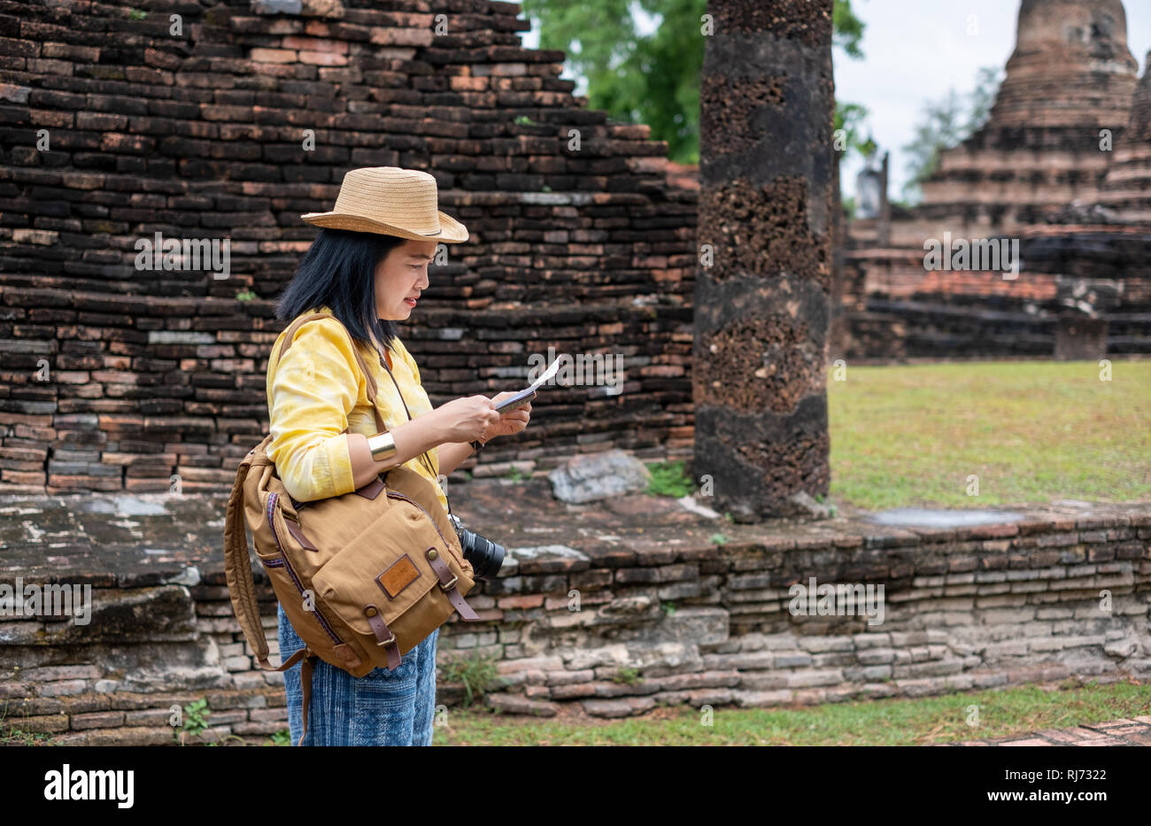 Tourisme asiatique femme voir la carte à l'ancienne pagode du temple thai architecture à Sukhothai, Thaïlande. Female traveler en thai style décontracté chiffons visite Banque D'Images