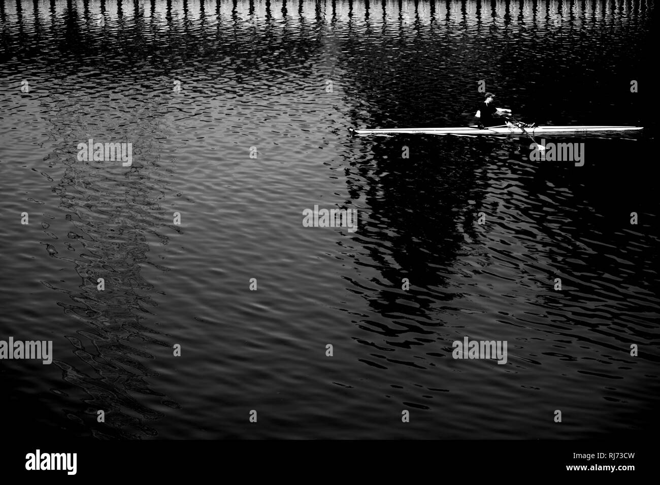 Sportruderboot durchschneidet ein eine dunkle abstrakte Wasseroberfläche, Banque D'Images