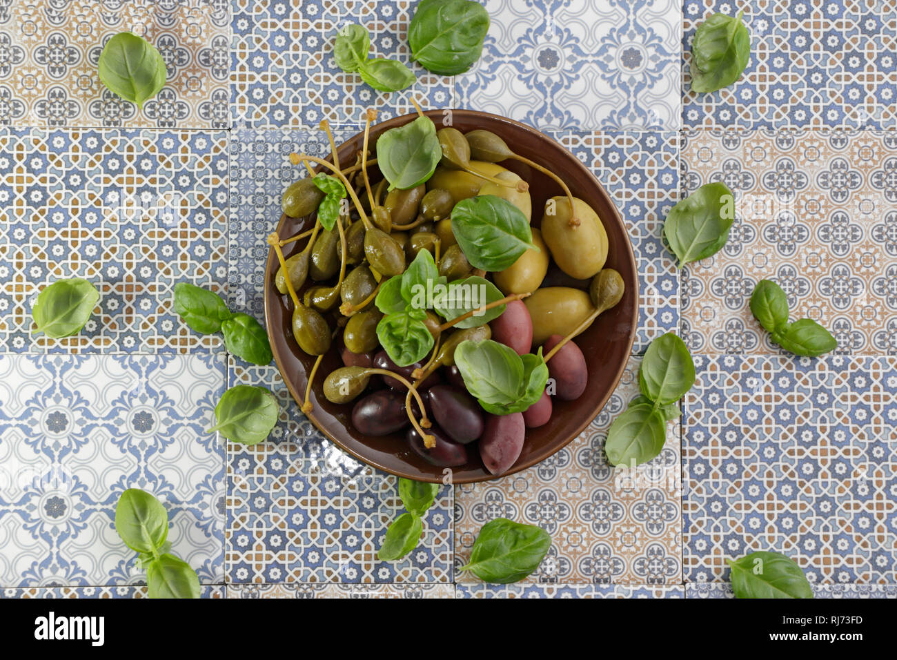 Teller mit Oliven, Kapern und auf blauen gemusterten Kräutern méditerranée Fliesen Banque D'Images