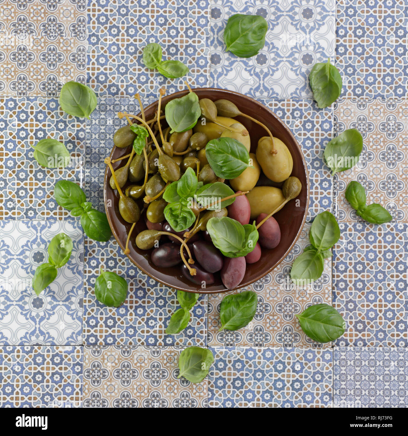 Teller mit Oliven, Kapern und auf blauen gemusterten Kräutern méditerranée Fliesen Banque D'Images