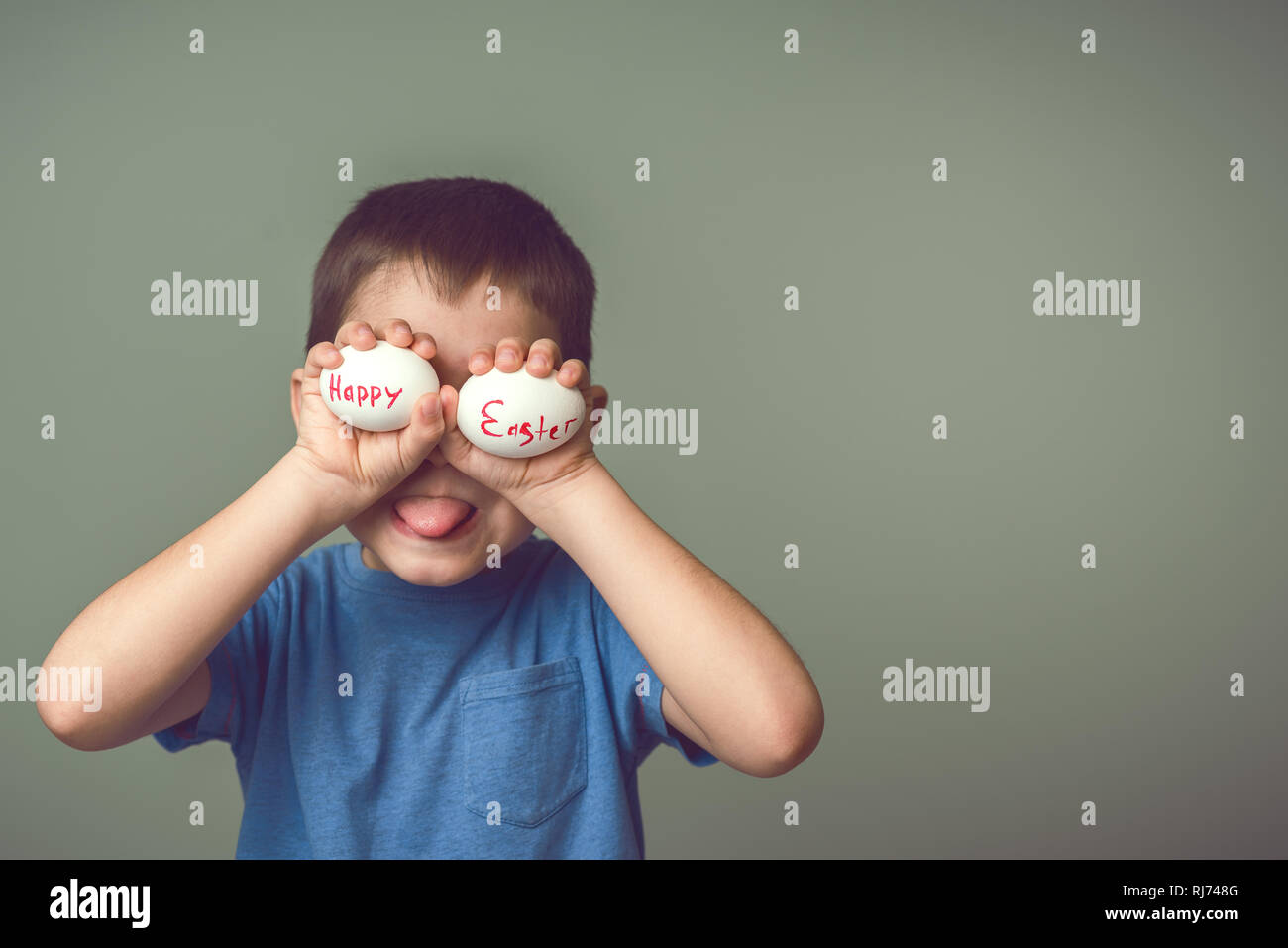 Un enfant est titulaire d'oeufs de Pâques à proximité des yeux avec l'inscription Joyeuses Pâques. Fond vert. Idées de Pâques. L'espace pour le texte. Les oeufs de Pâques. La tonalité de l'image. Banque D'Images