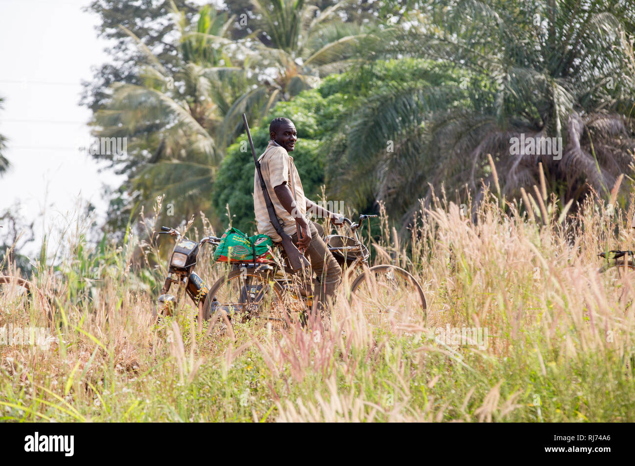Village de Karfiguela, Banfora, région de Cascades, Burkina Faso, 6 décembre 2016; chasseur sur son vélo sur le chemin de la recherche de viande de brousse. Banque D'Images