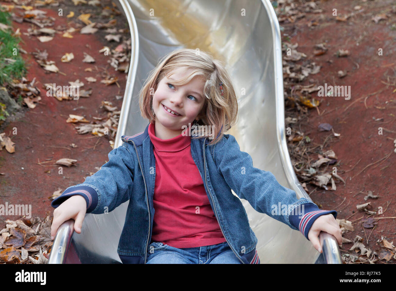 Siebenjähriges Mädchen auf einem Kinderspielplatz auf einer Rutsche Banque D'Images