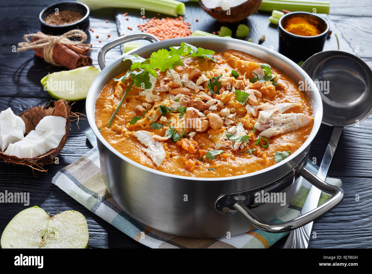Soupe Mulligatawny épicé copieux avec de la viande de poulet frit arrosé avec dans un chaudron de cajou sur une table en bois noir avec des ingrédients, Affaires indiennes et l'engl Banque D'Images